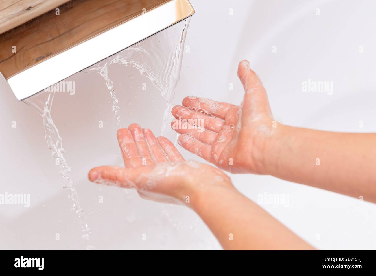 Das Kind wäscht seine Hände mit Seife unter einem Wasserhahn mit sauberem Wasser. Seifige Kid`s Hände Nahaufnahme auf weißem Hintergrund. Hygienekonzept. Krankheitsvermeidungen Stockfoto